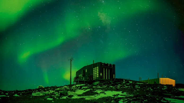 Aurora australis appearing as ribbons of green-blue light above Davis station in Antarctica.