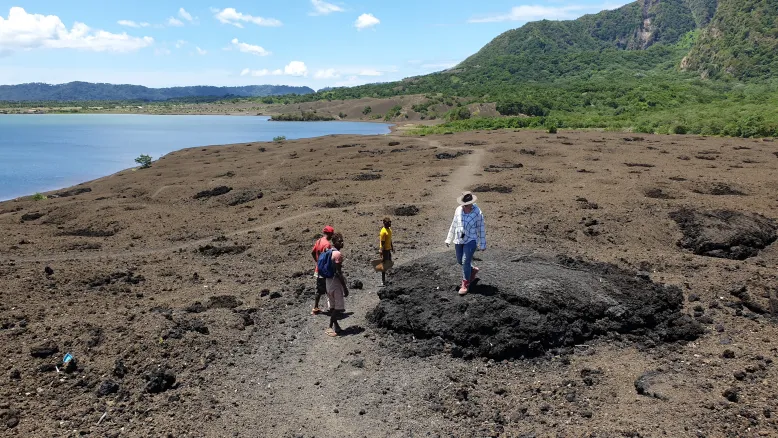 Four people standing on a lava bomb on a volcanic plain in Papua New Guinea.