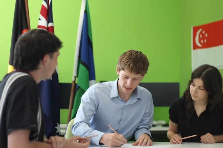Three graduate meteorologists look at their work on the table in front of them