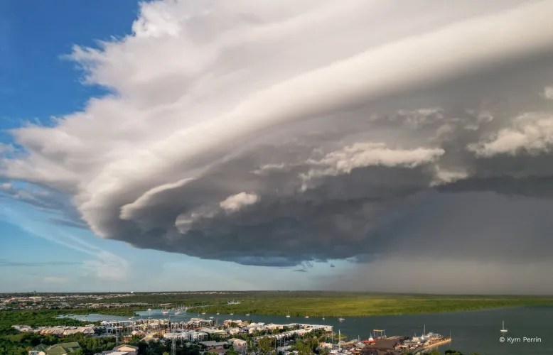Clouds of an approaching thunderstorm swell as rain falls from the sky.