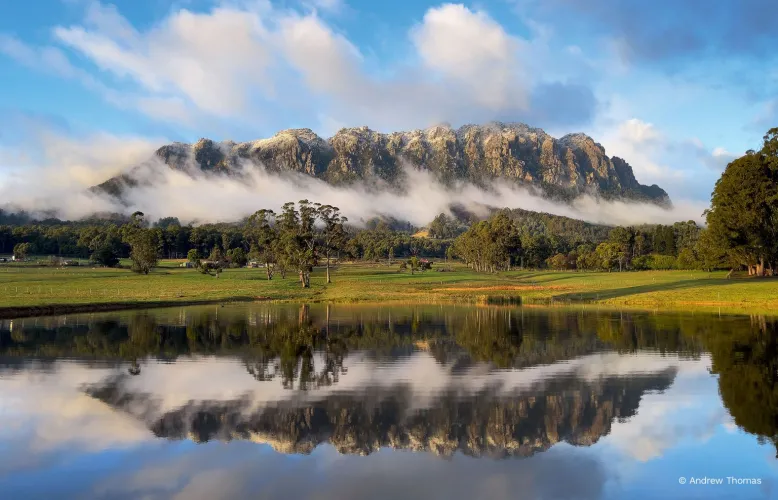 Fog surrounds the base of Mount Roland, while the rocky top of the mountain nestles into the clouds above.