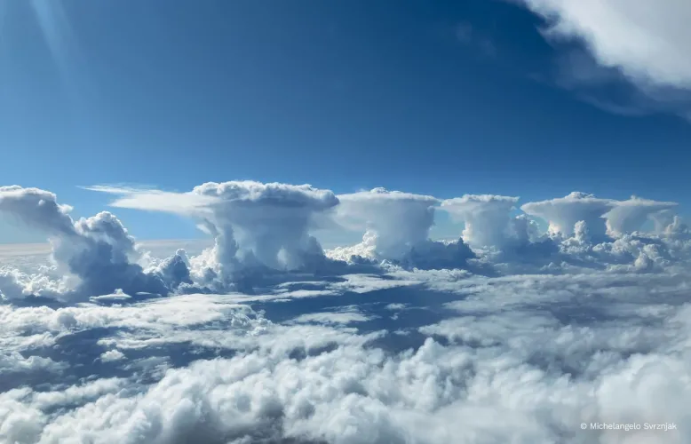Clouds of five thunderstorms are lined up, one after the other, leading off into the distance.