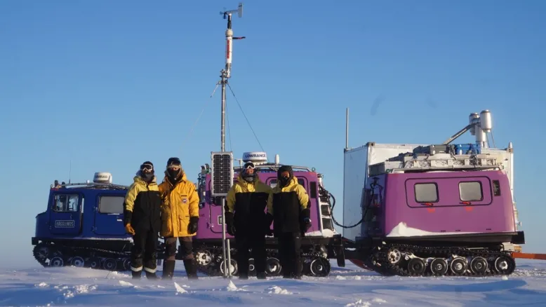Technical officer Brian and his crew mates stand in front of the Law Dome weather station with the Hagglund ice terrain vehicles behind them