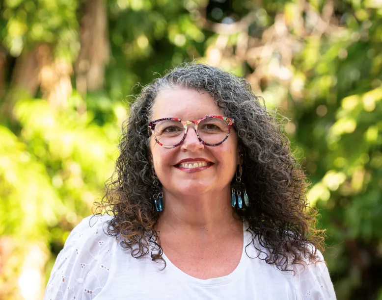 Photographer Kym Perrin stands in front of a natural environment.