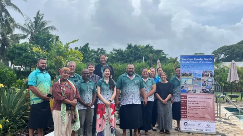 Staff from Bureau of Meteorology and Pacific agencies stand next to a sign for Weather Ready Pacific.