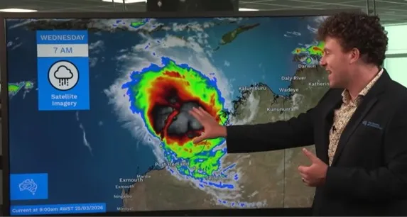 Meteorologist Angus Hines points at screen.