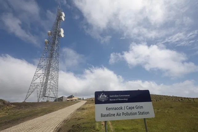 Path leads up a green hill past a radio tower. A sign reads: Australian Government, Bureau of Meteorology, Kennaook / Cape Grim Baseline Air Pollution Station.
