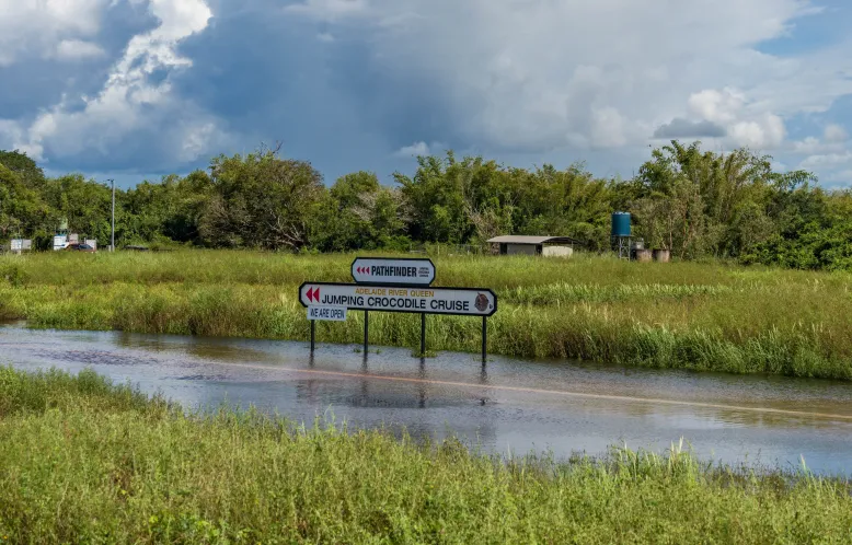 Flooding along the Adelaide River in the Northern Territory in a lush green environment with heavy clouds in the background.