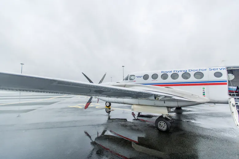 White Royal Flying Doctor Service aeroplane on a gloomy and wet tarmac.
