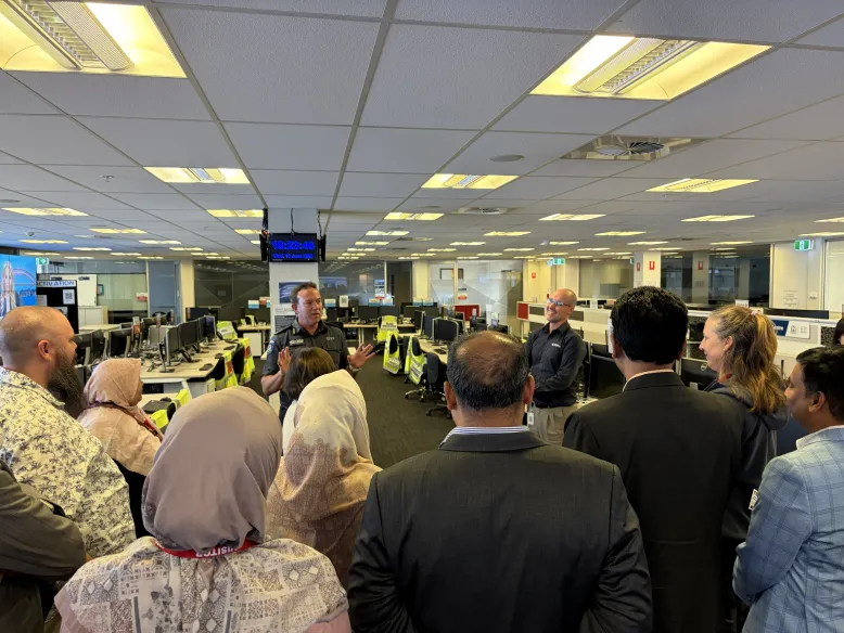 About 10 people listen to an expert in an office explain what they do.