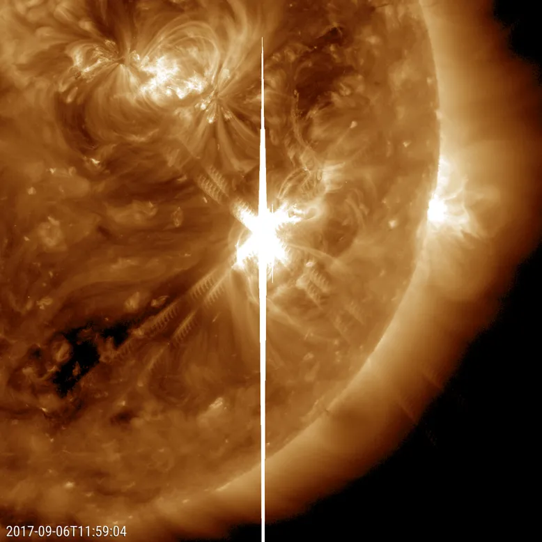 Close-up of the sun showing a bright solar flare erupting from the surface, with loops of plasma surrounding a white explosion near the centre.